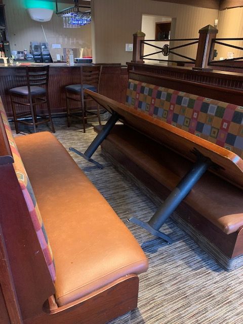 Restaurant booth seating with orange bench and wood tables in a carpeted dining area
