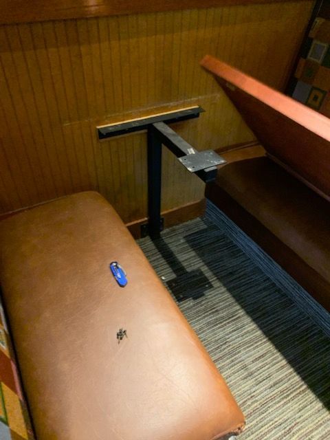 Wood-paneled booth with tan benches and a small blue object on the seat, viewed from above.