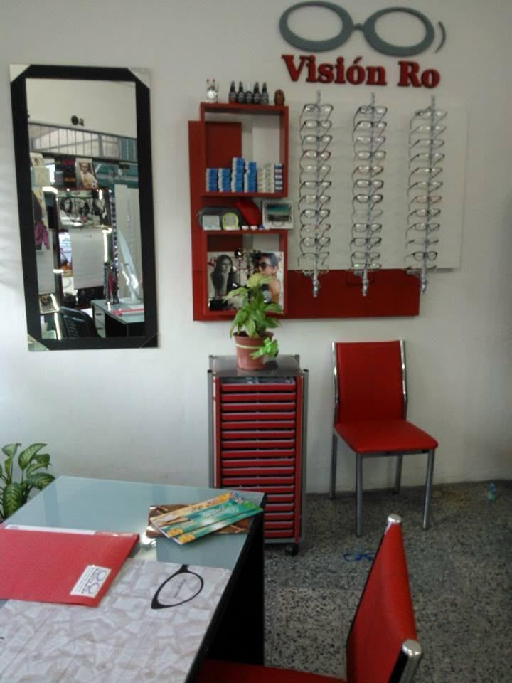 Gafas junto a papeles y una tarjeta médica azul sobre un escritorio cerca de una computadora portátil.