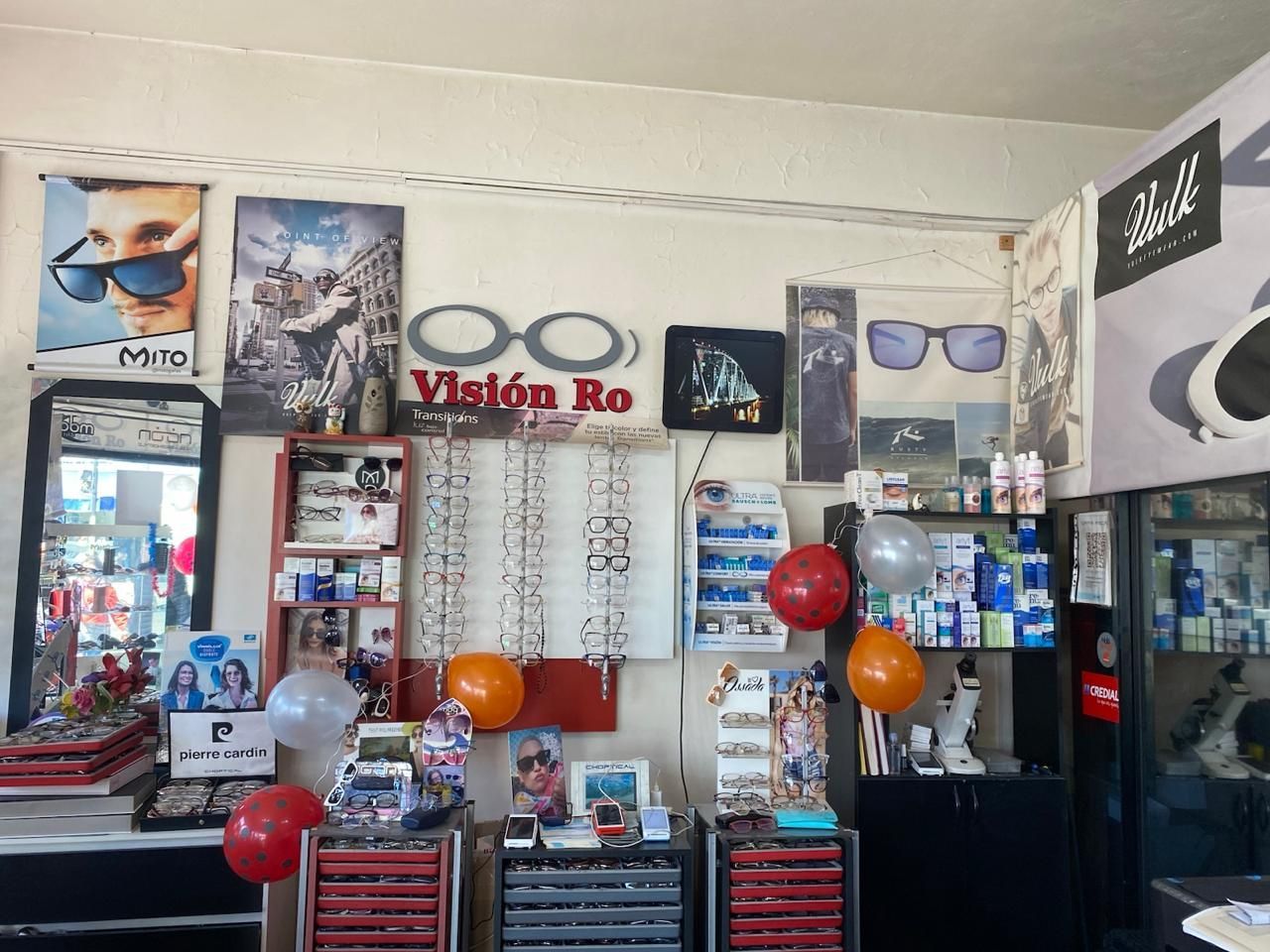 Variedad de gafas, herramientas y tornillos dispuestos sobre un banco de trabajo en un taller de reparación de ópticas.