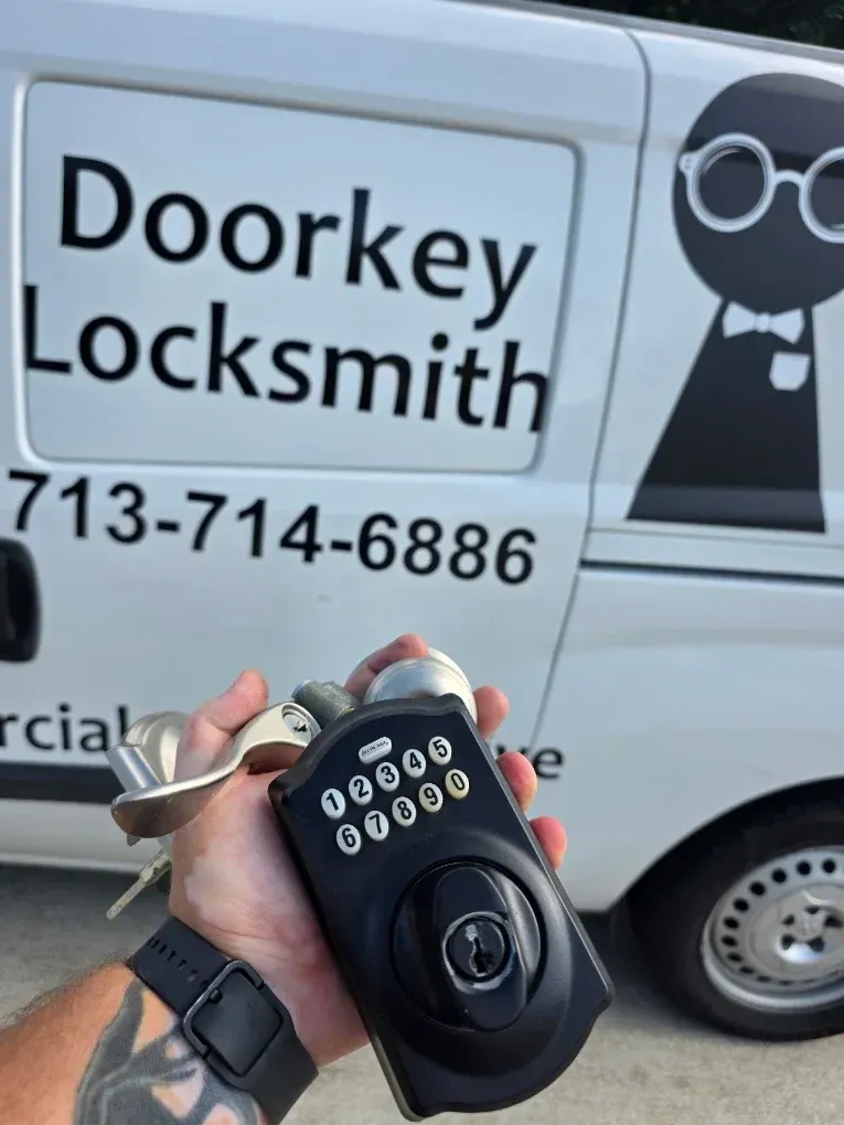 Hand holding a black keypad lock in front of a Doorkey Locksmith van with phone number.