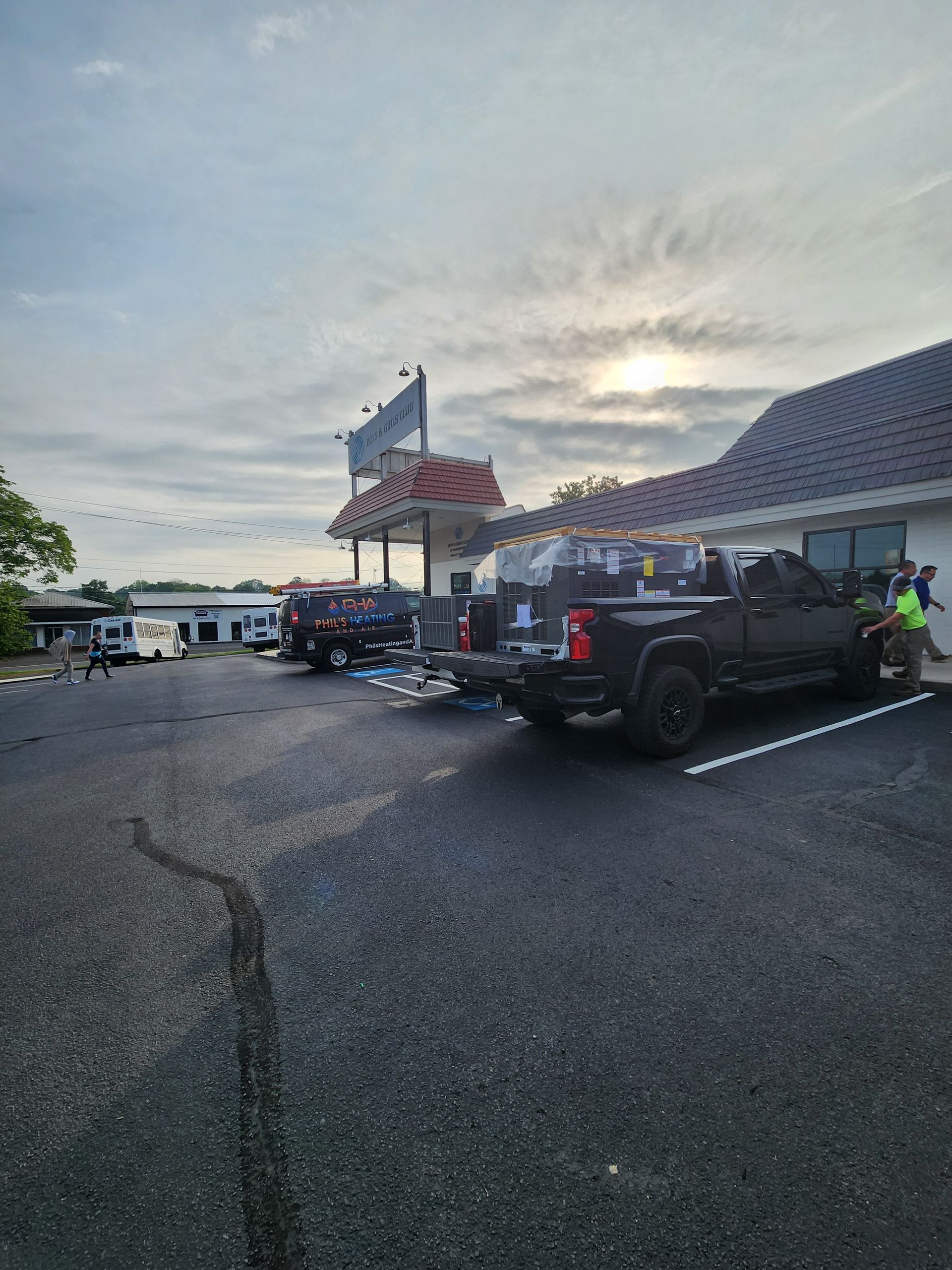 Several off-road vehicles parked outside a building at dusk under a cloudy sky.