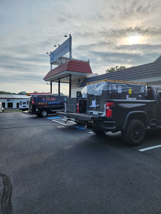 Parked pickup trucks with trailers in a gravel lot beside a building at dusk