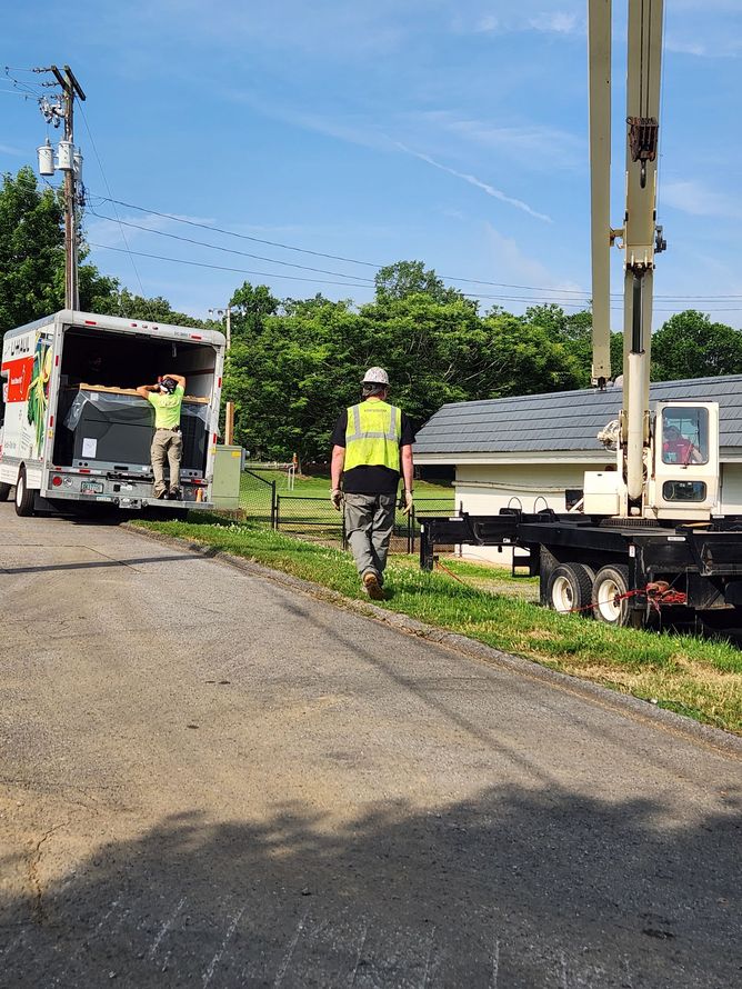 Rail worker in neon vest beside a truck and rail cart on a sunny rural roadside