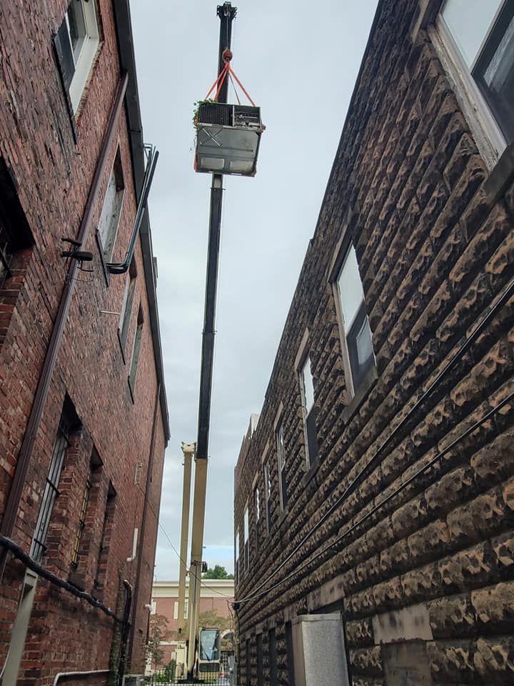 Crane lifting a small platform between two brick buildings in a narrow alley