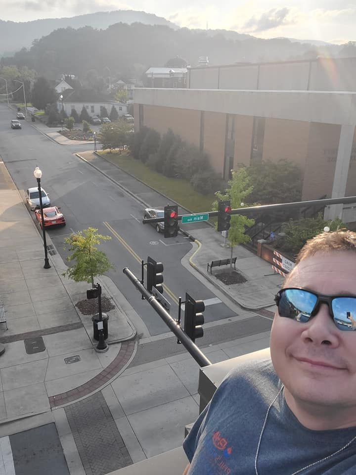 Selfie from a rooftop overlooking a street intersection at sunset, with mountains in the background.