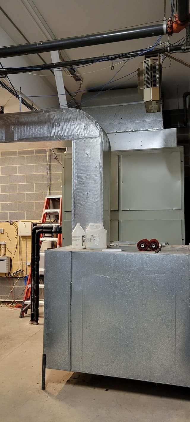 Industrial room with large silver ductwork and metal HVAC equipment in a warehouse-like interior