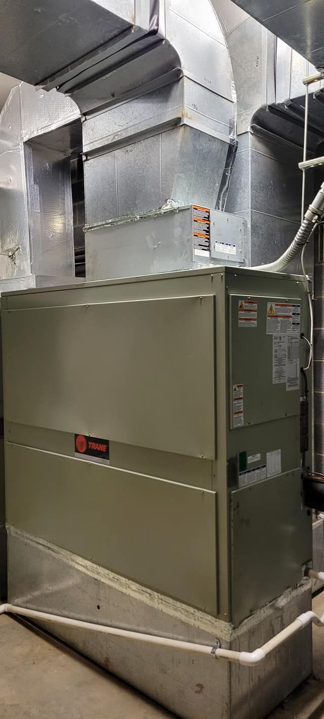 Large industrial HVAC unit with metal ductwork in a mechanical room