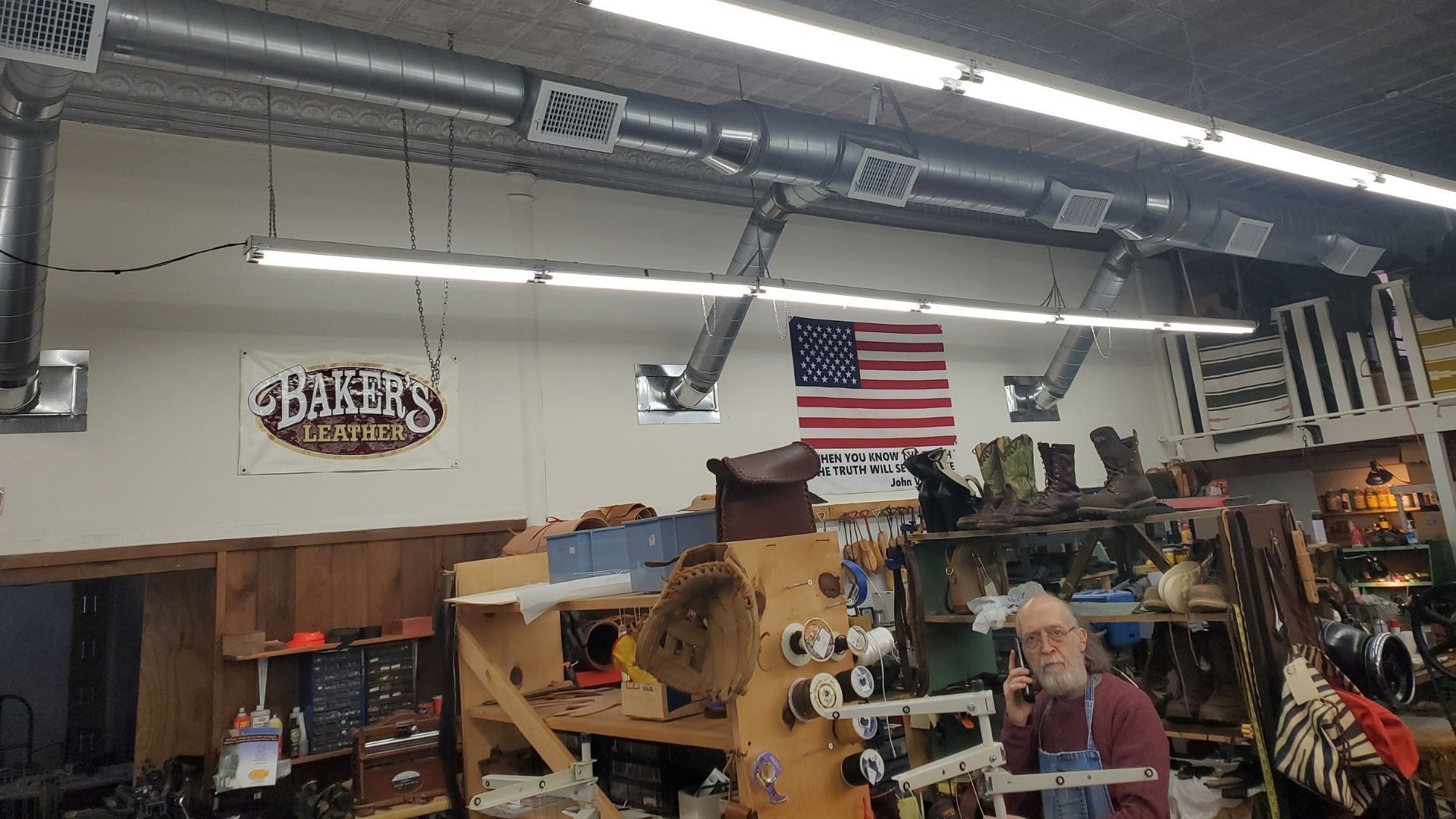 Indoor market shop with shelves of goods, an American flag, and a sign reading “Bakers.”