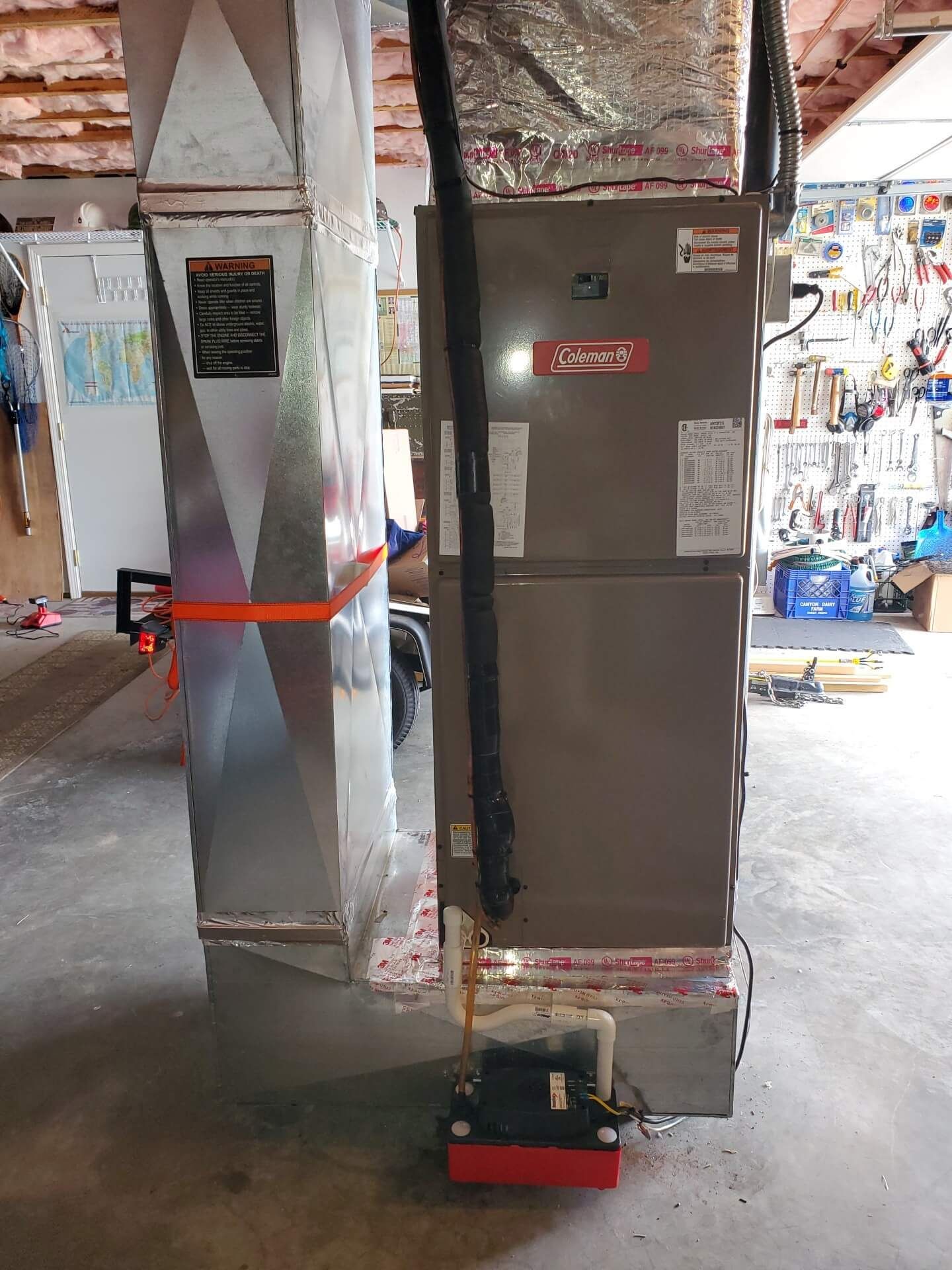Two standing metal cabinets wrapped in protective material, one with a small red dolly at its base.