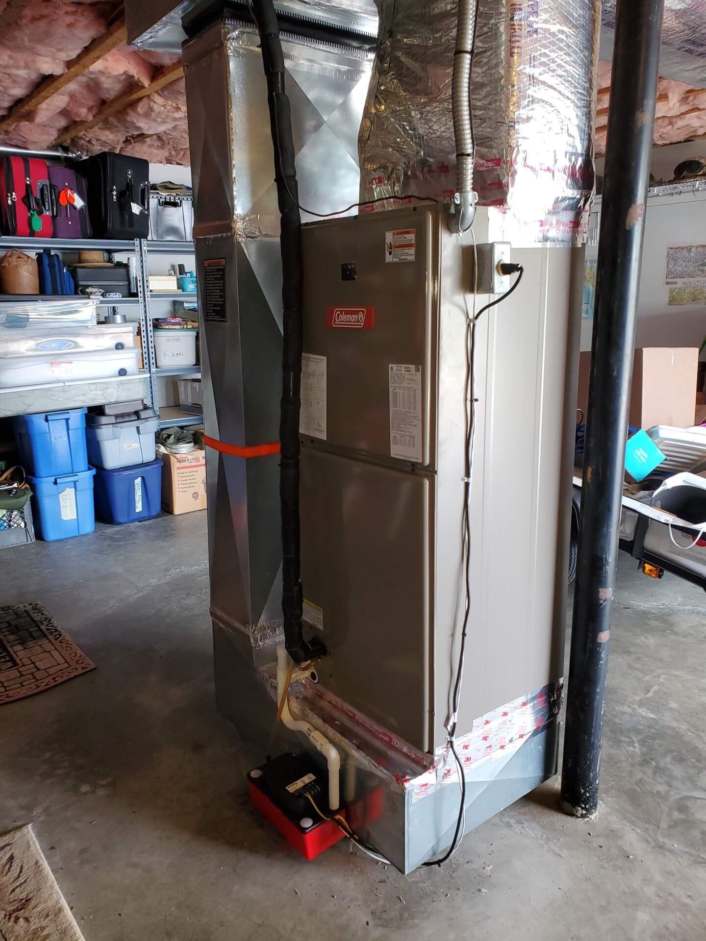 Basement furnace and HVAC unit with ductwork and exposed insulation in a utility room