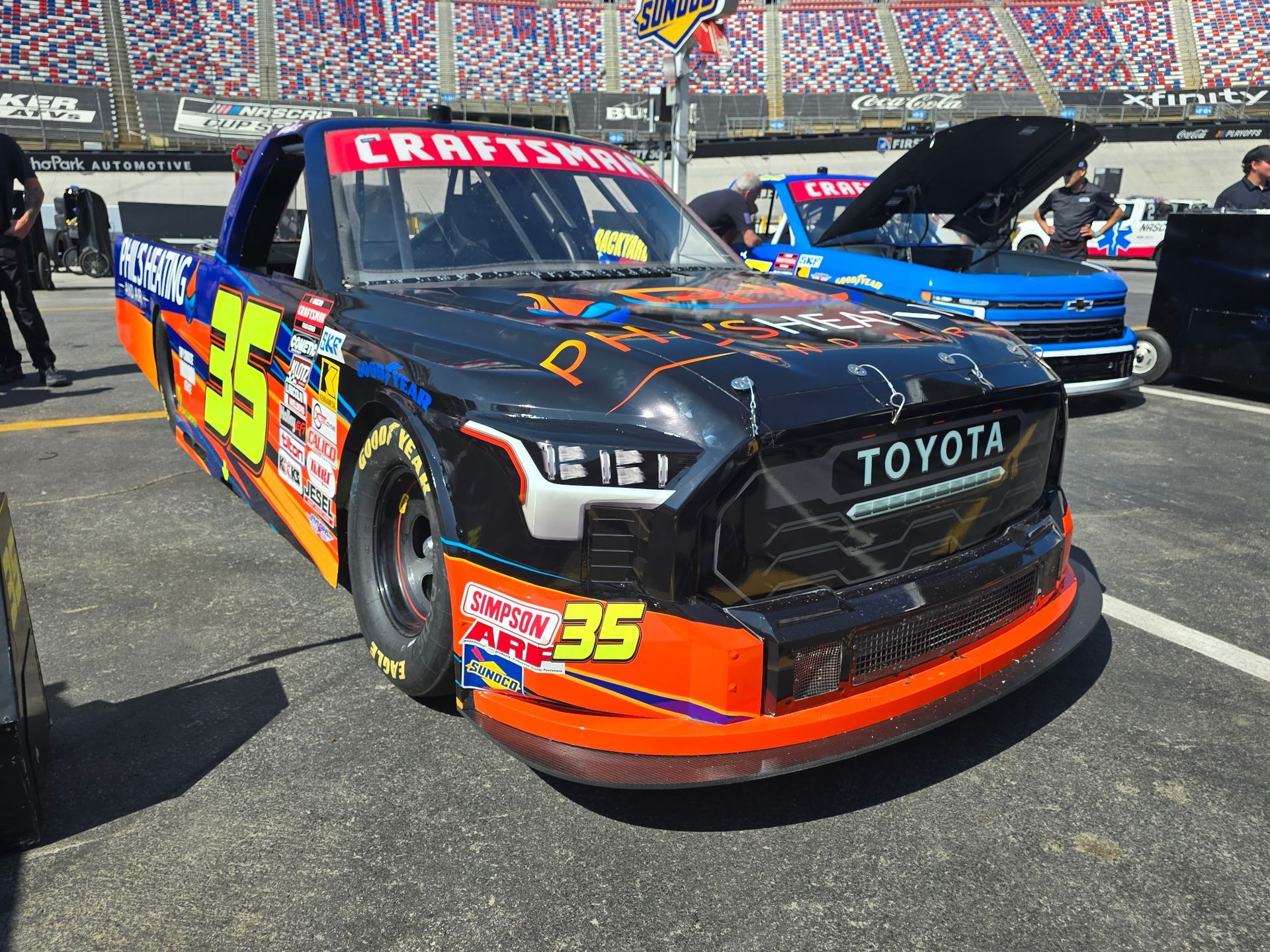 Black Toyota race car with orange accents and number 95 on a track, stadium seats in the background