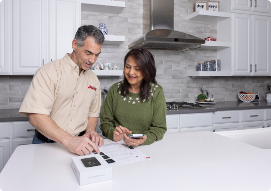 Preventative Maintenance Plans Two people at a kitchen counter reviewing a device, with one pointing at the screen.