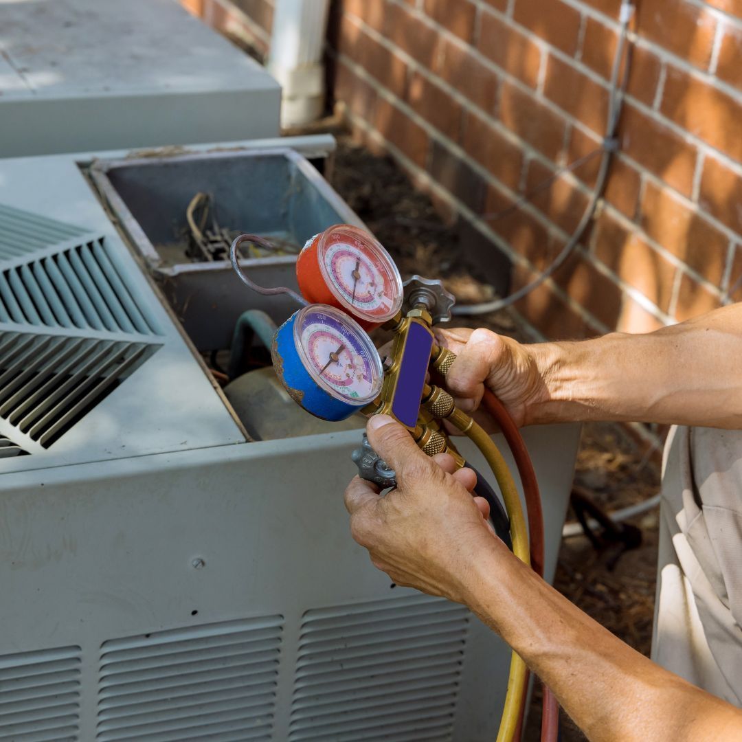 Technician using manifold gauges to service an outdoor air conditioning unit