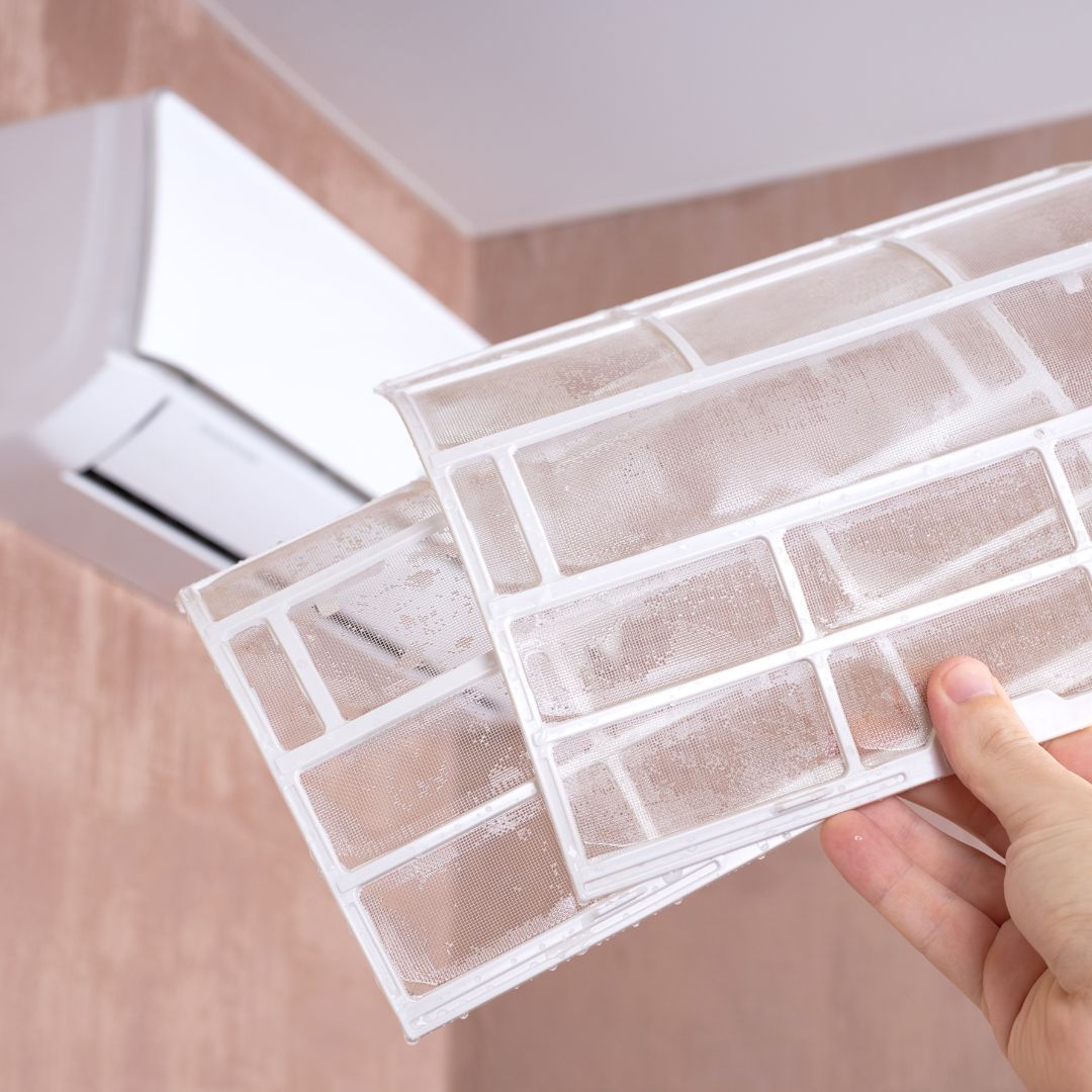 Our HVAC Services A person is holding a filter in their hand in front of an air conditioner.