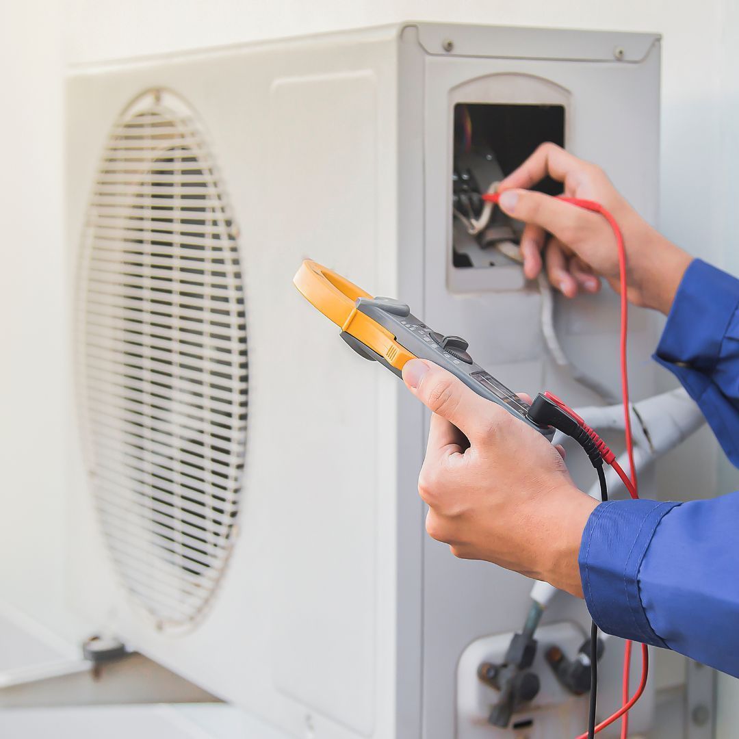 Contact Us Technician testing HVAC unit wiring with a multimeter and probe leads