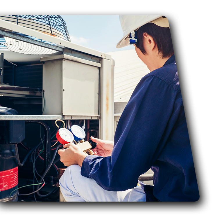 Technician checking HVAC unit with gauges beside an outdoor air conditioner