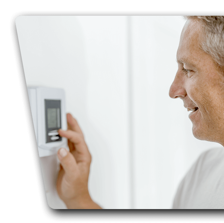 Contact Us Man adjusting a wall thermostat with a smile in a bright room