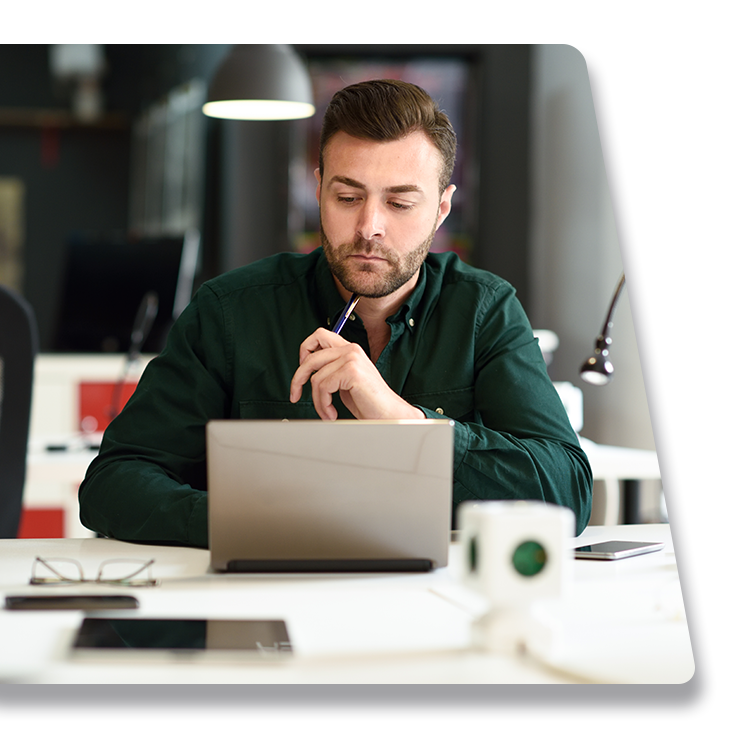 Contact Us Man in a green shirt working on a laptop at a desk in a modern office