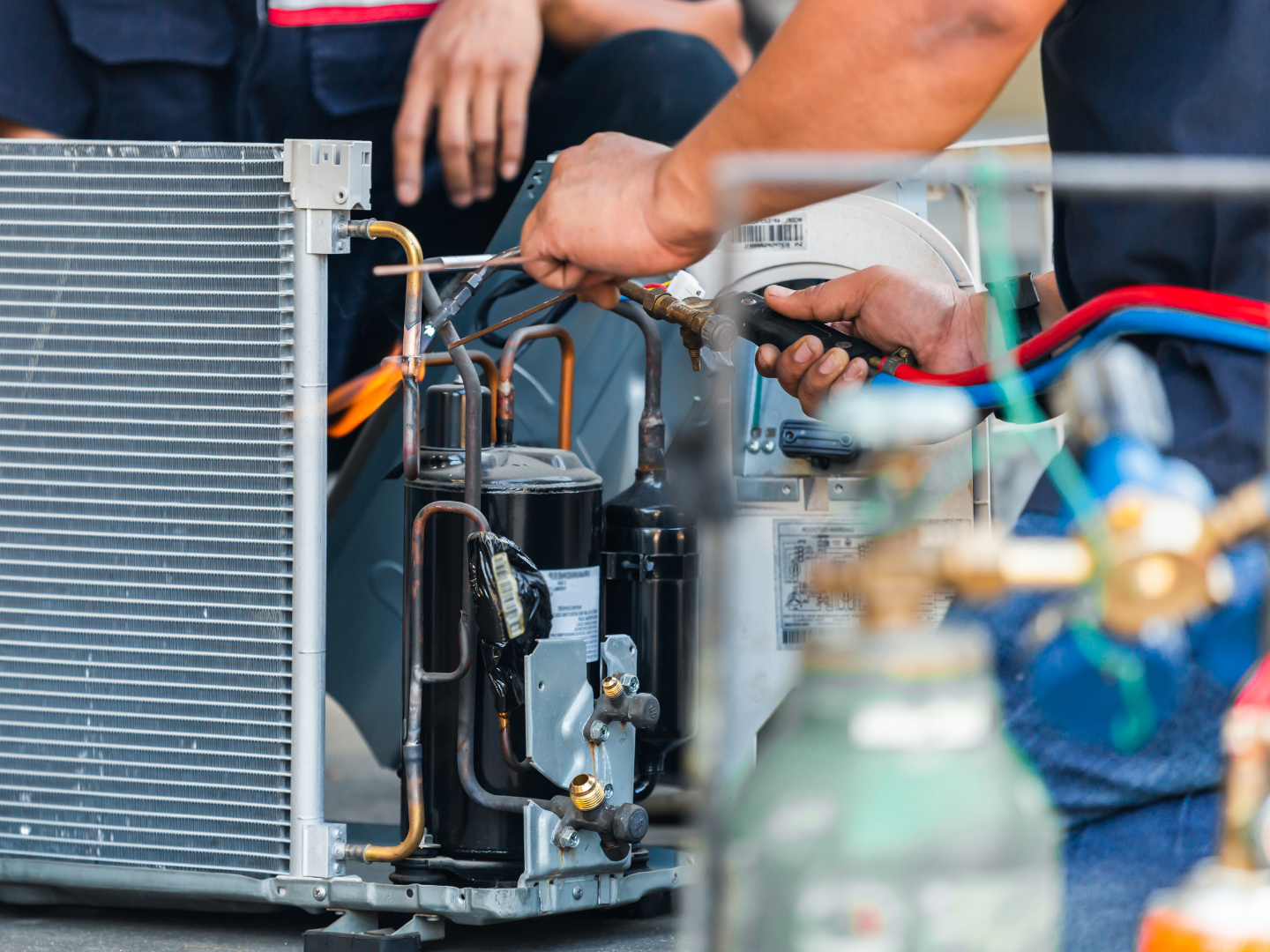 Contact Us Technician repairing an air conditioner compressor with tools and copper tubing outdoors