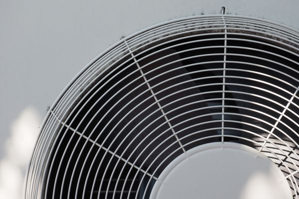 Close-up of a black circular fan grille against a light background