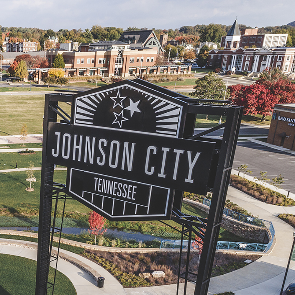 Johnson City, Tennessee sign in a landscaped downtown park with buildings and fall trees beyond
