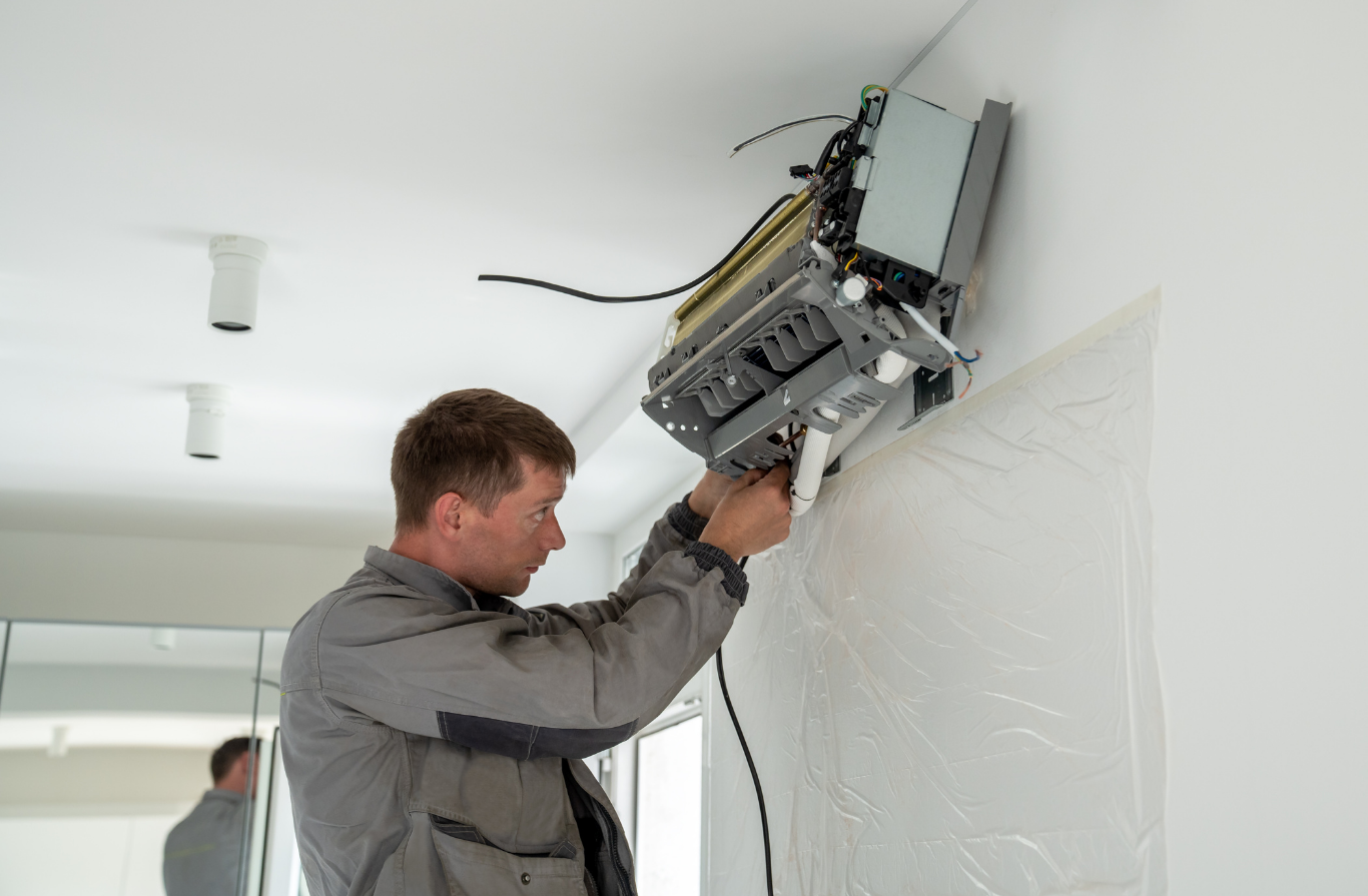 Mini Splits Technician repairing a wall-mounted device in a bright room