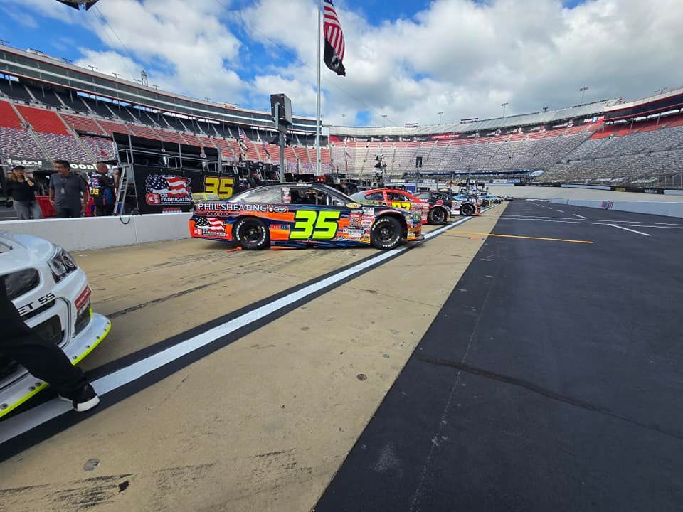 NASCAR stock cars on pit road at a racetrack, with one black-and-orange car numbered 35 in the foreground