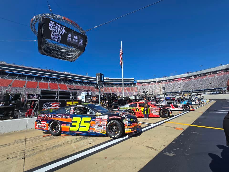 NASCAR race cars lined up on pit road at a sunny stadium track, car 35 in the foreground.
