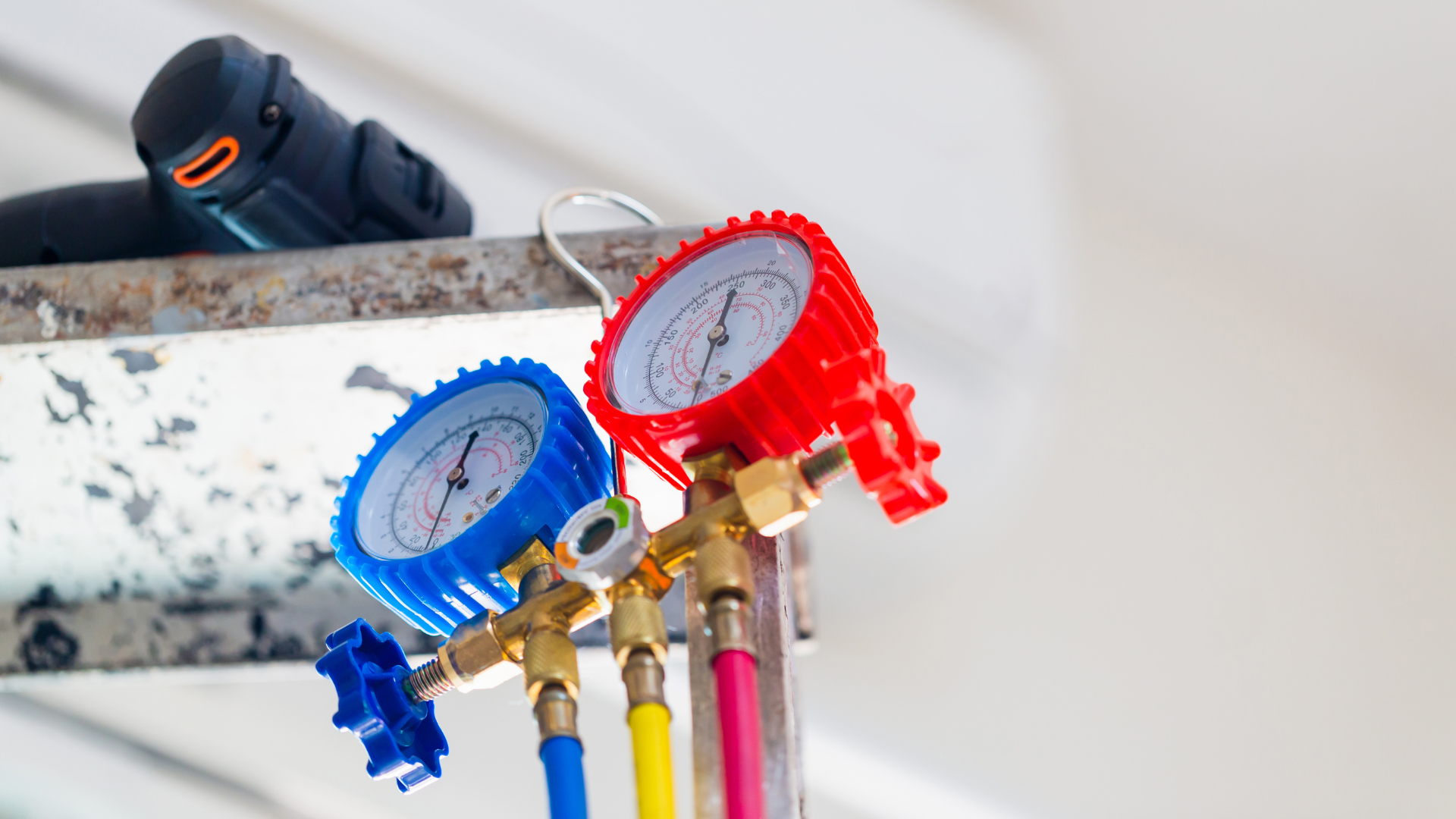 Blue and red pressure gauges with hoses, likely for HVAC maintenance.