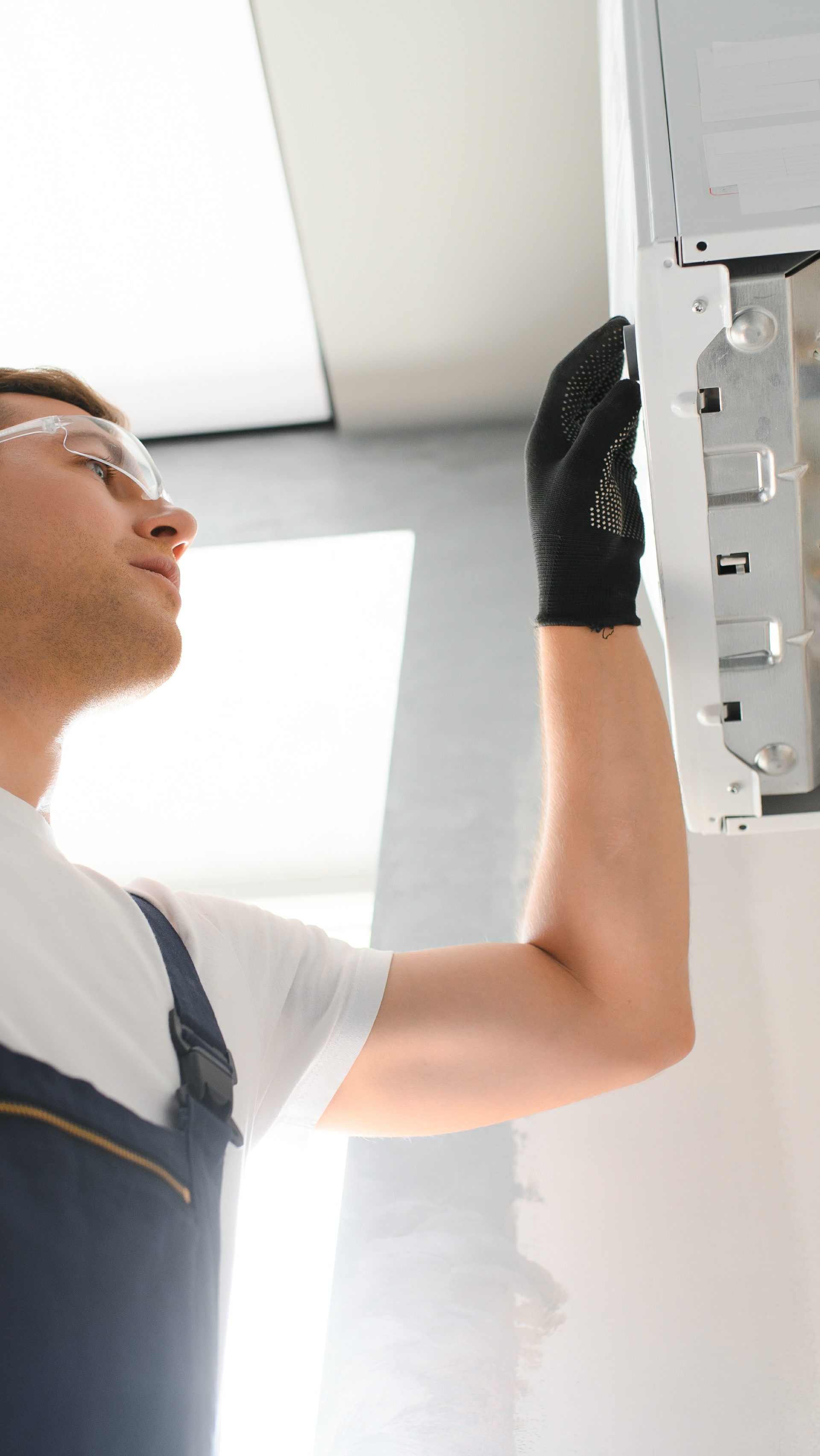 Contact Us Worker in a white shirt and black glove inspecting a ceiling fixture with a tool