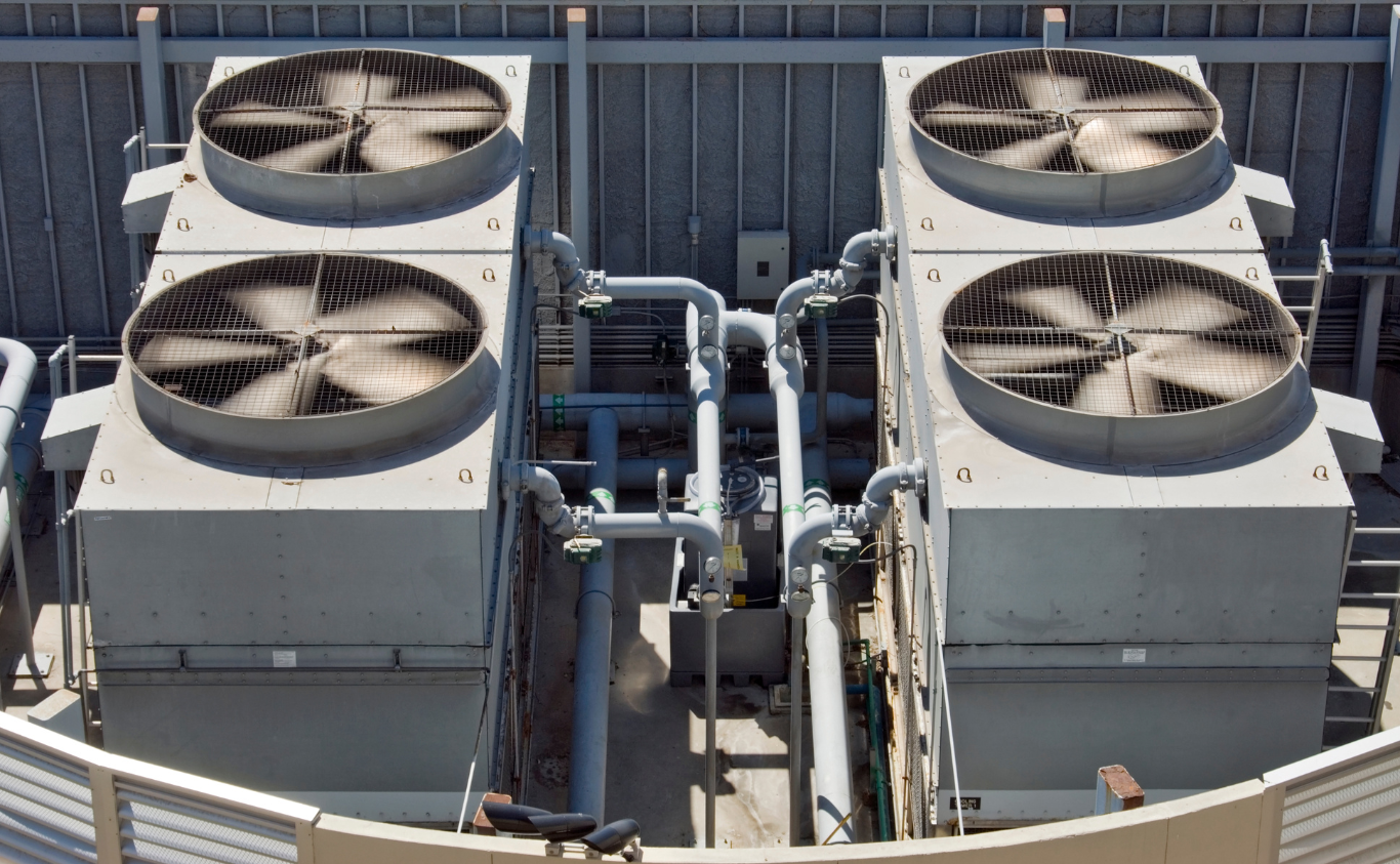 Four large rooftop HVAC fans on industrial equipment units outdoors.