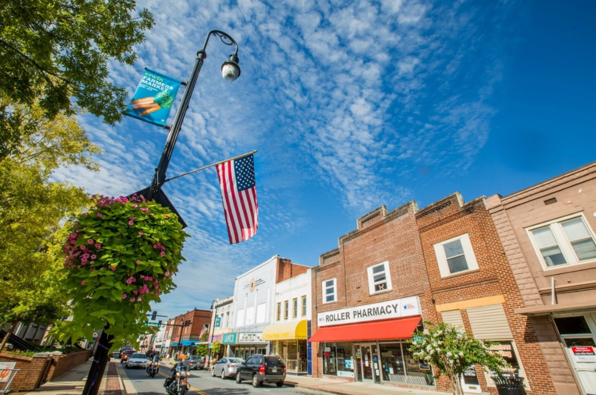 Main street with shops, hanging flags, and a bright blue sky with scattered clouds