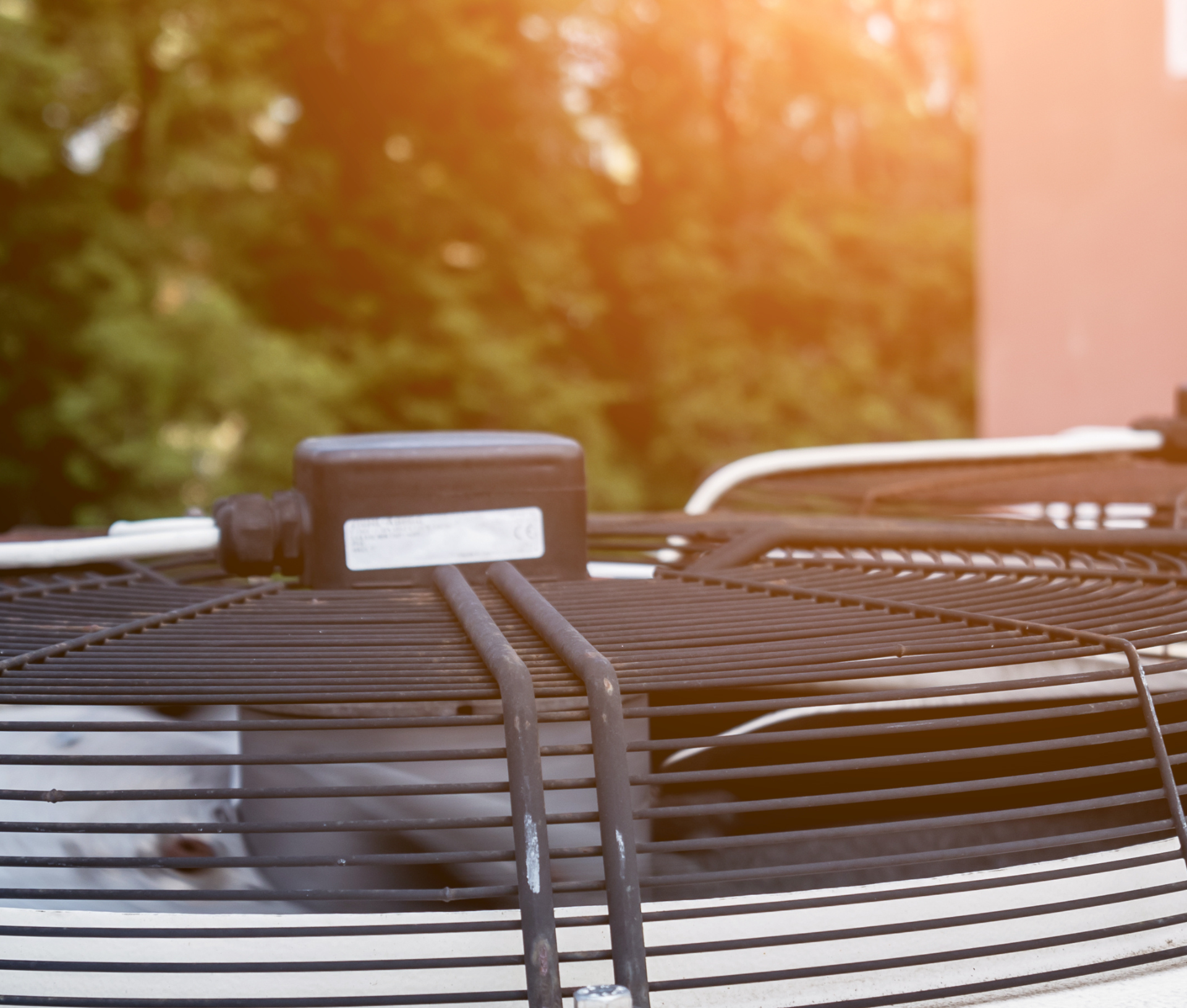 Contact Us Outdoor air conditioner unit with metal grille and warm sunlight in the background