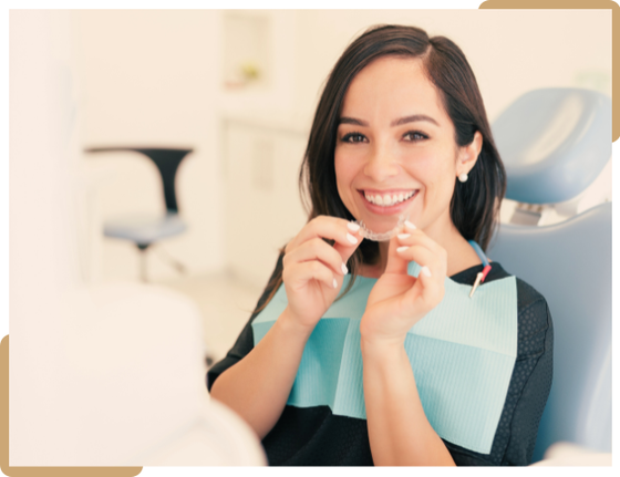 Woman holding a clear Invisalign aligner at a dental clinic in Langley, BC