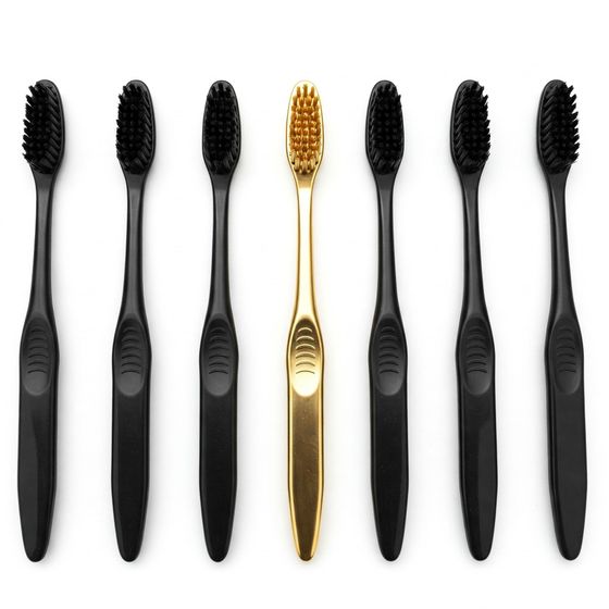 Row of black toothbrushes with a single gold one at center — representing the premium dental care experience at Ethos Dental Studio