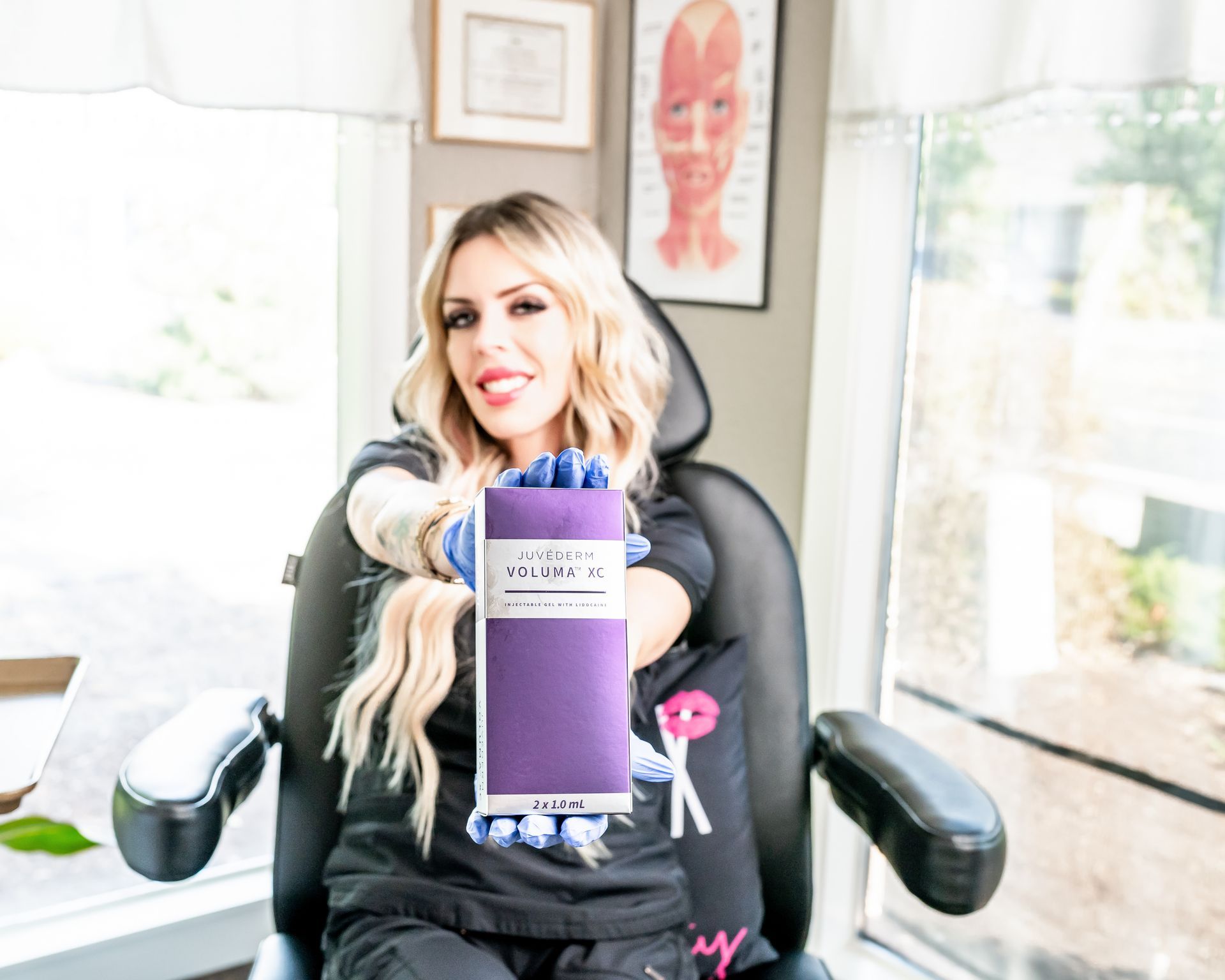 A woman is sitting in a chair holding a purple box.