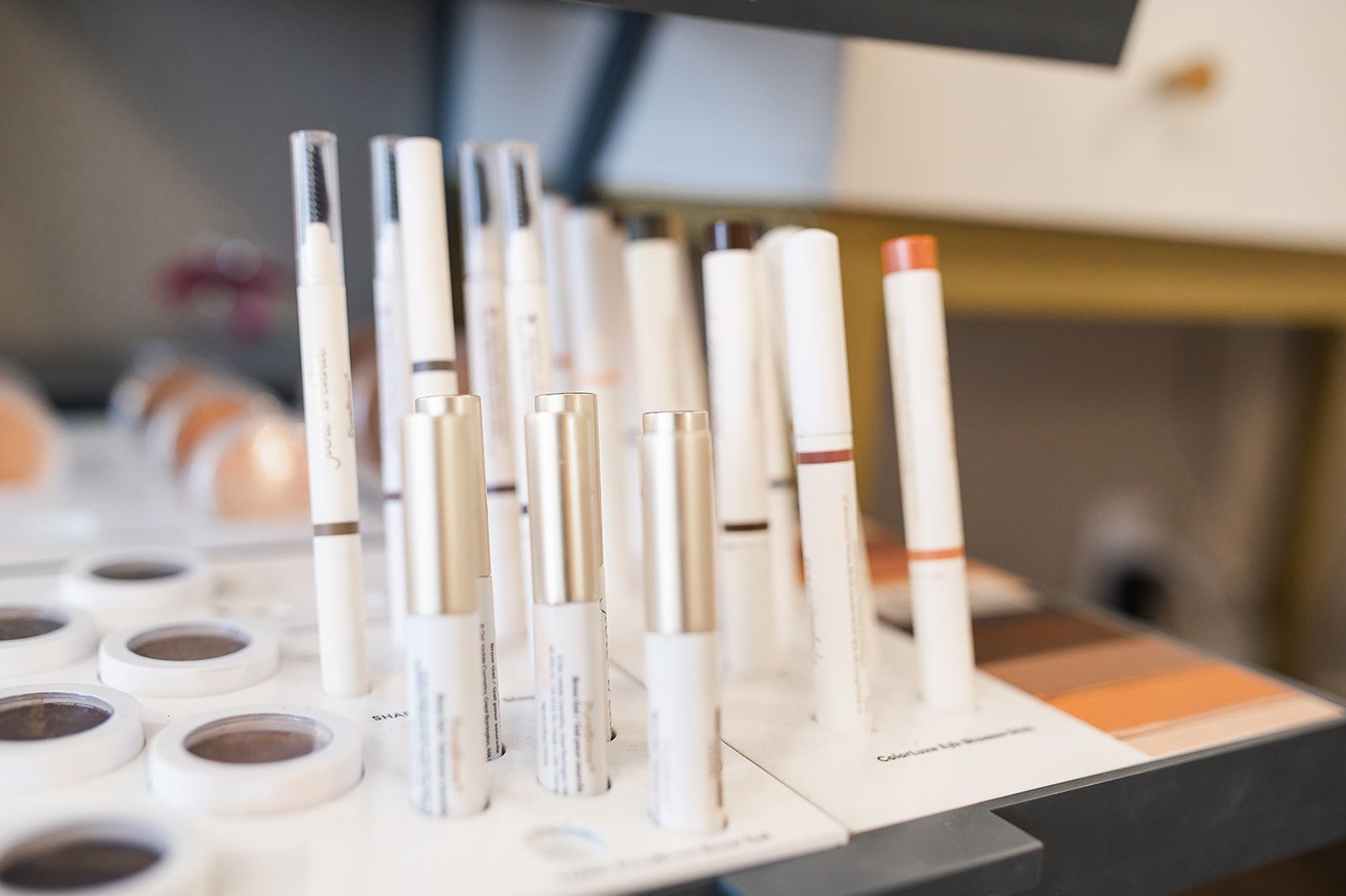 A woman is sitting at a table with bottles of cosmetics.