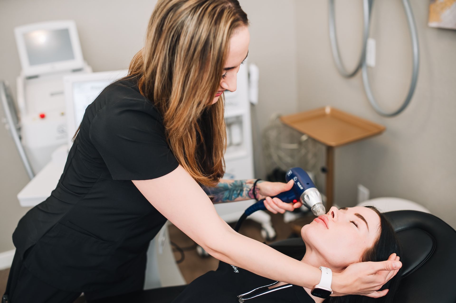 A woman is giving a woman a treatment on her face.