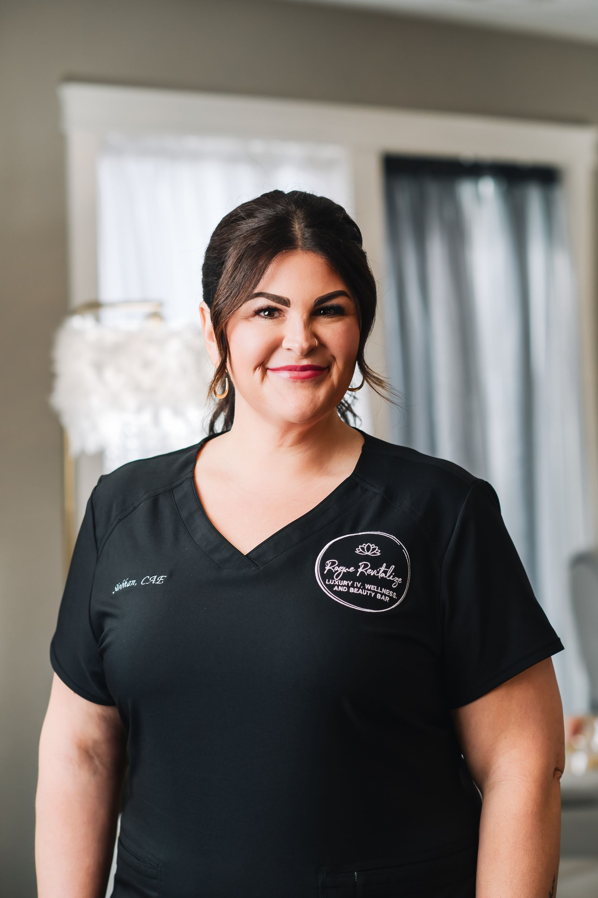 A woman in a black shirt is smiling and standing in a room.
