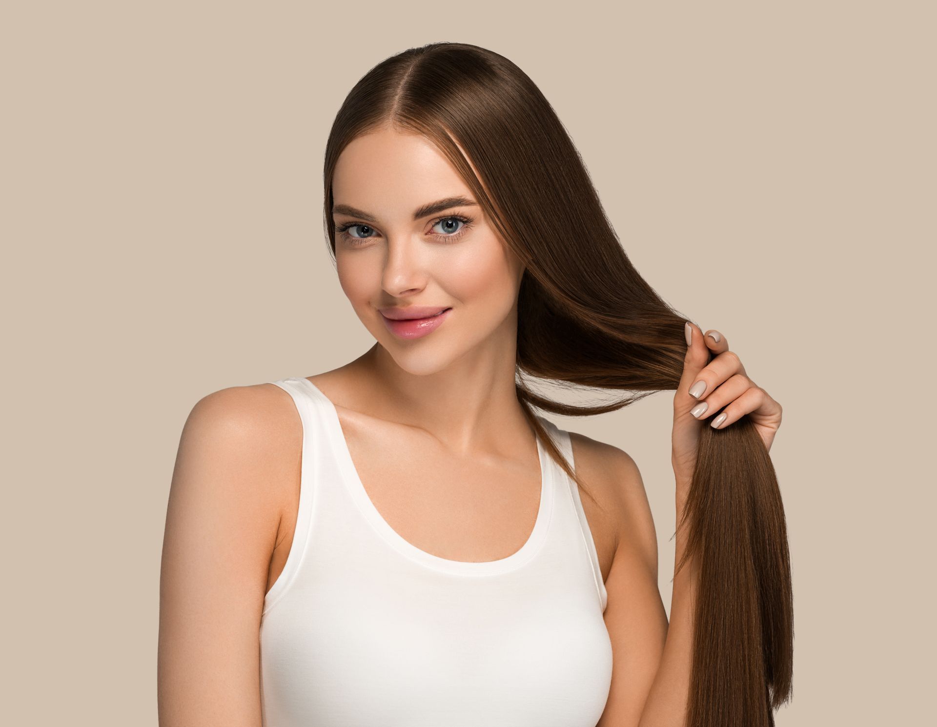 A woman in a white tank top is holding her long hair.