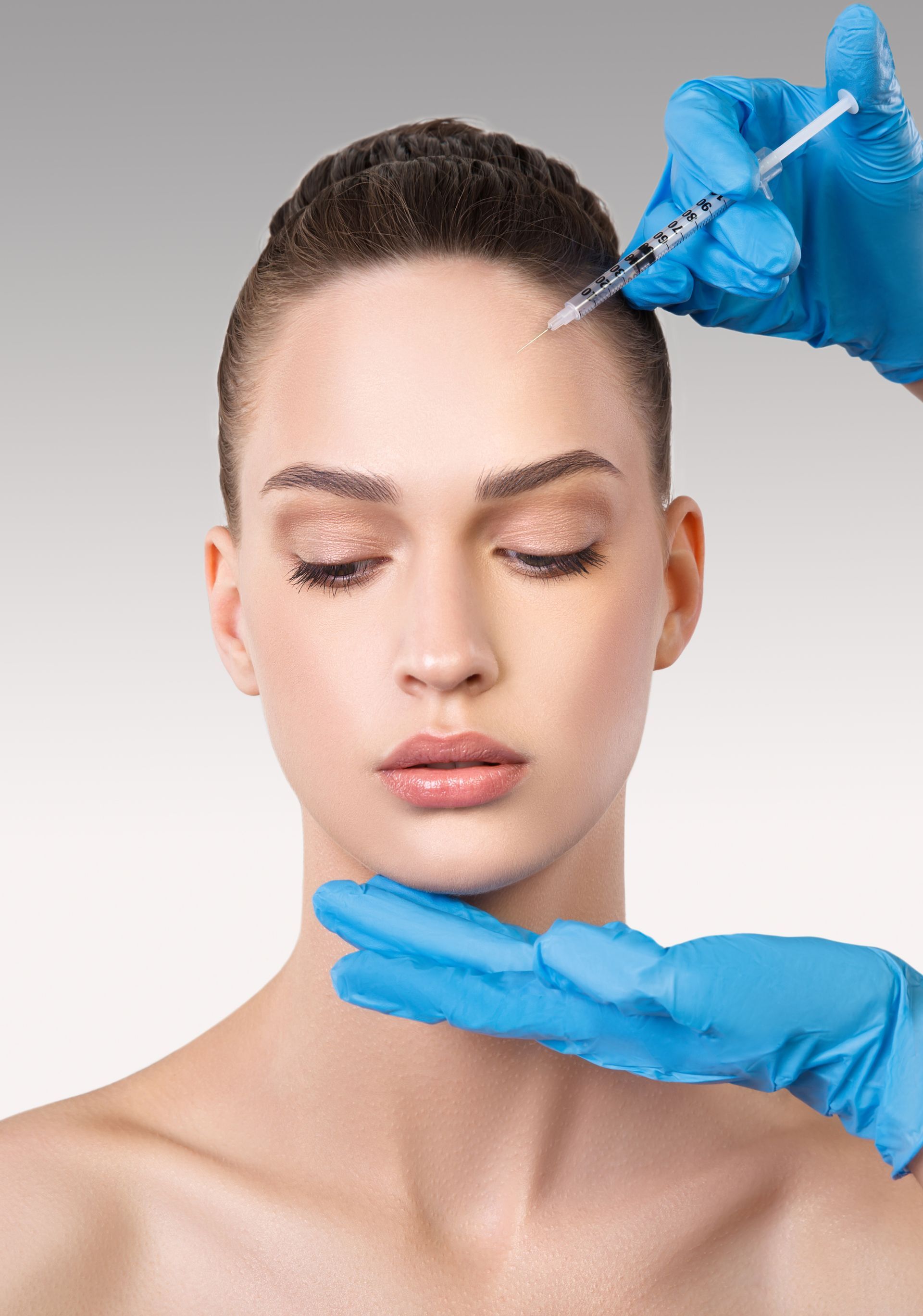 A woman is getting a botox injection in her forehead.