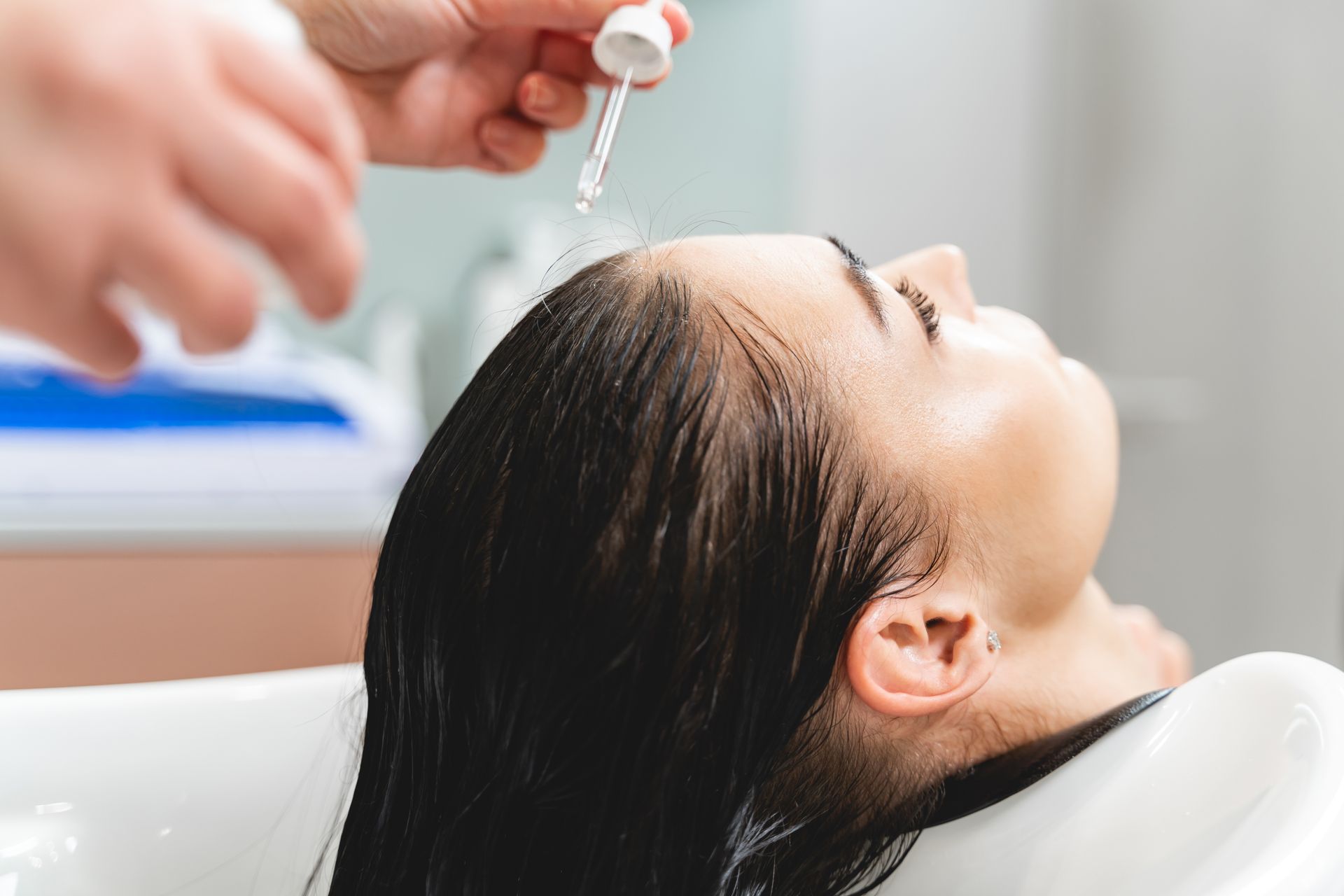 A woman is getting her hair washed in a sink at a salon.