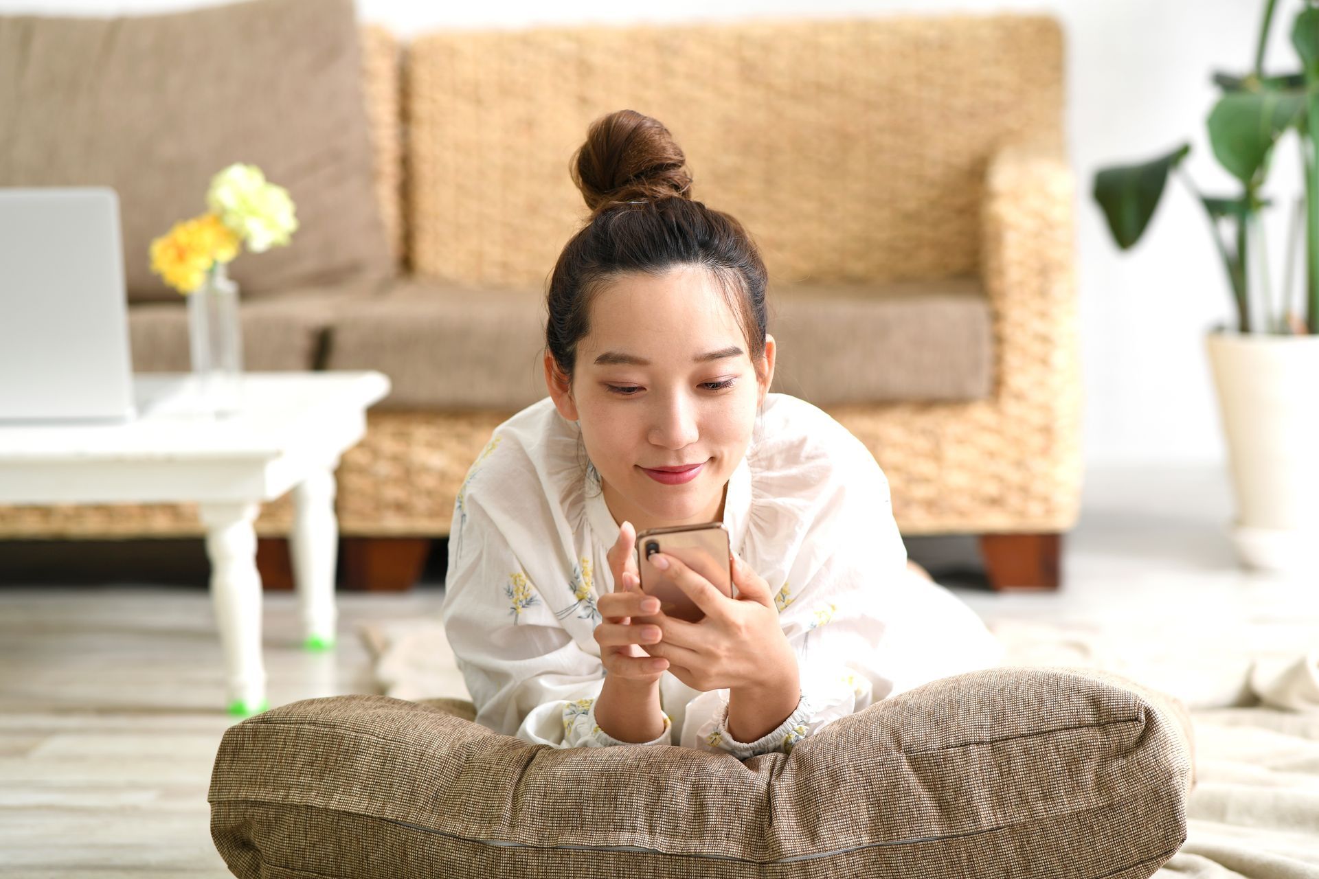 A woman is laying on the floor using a cell phone.