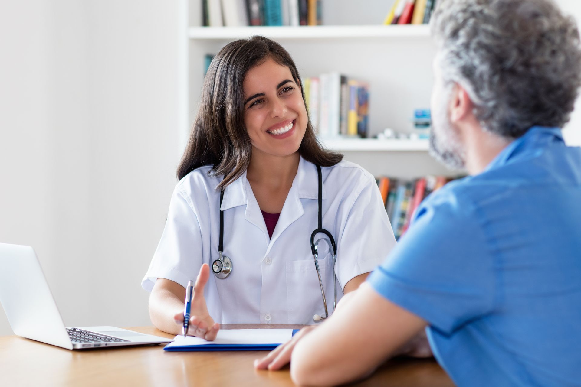 A doctor is sitting at a desk talking to a patient.