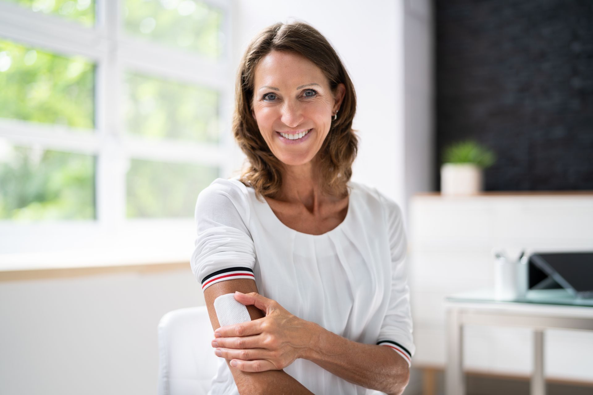 A woman is smiling while getting an injection in her arm.