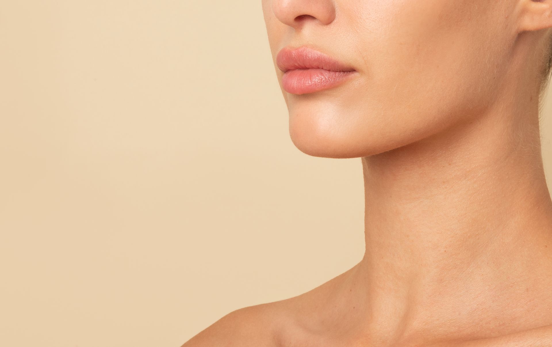 A close up of a woman 's neck and face on a beige background.