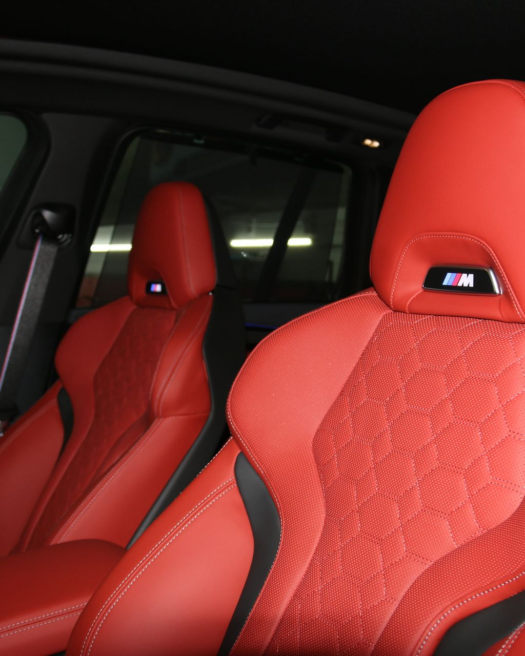 A person's hand wiping down the dark frame of a car door with a bright red cloth.