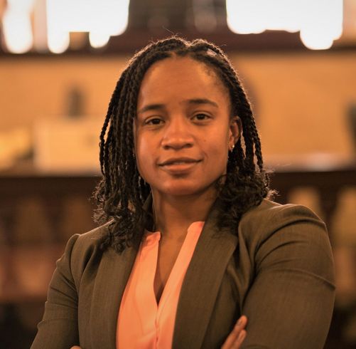 A woman with dreadlocks is posing for a picture with her arms crossed