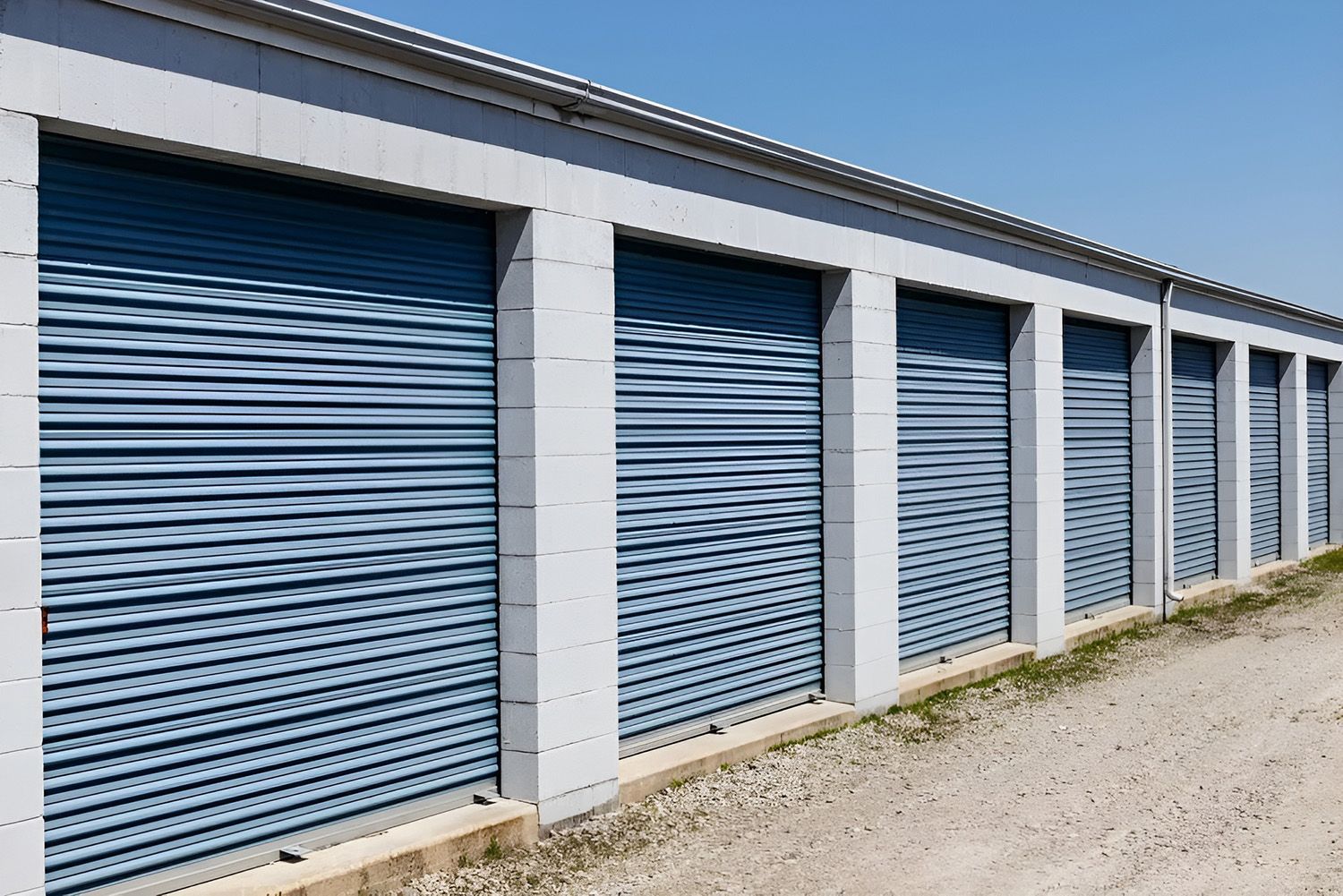Row of blue roller door storage units in a clean outdoor facility.